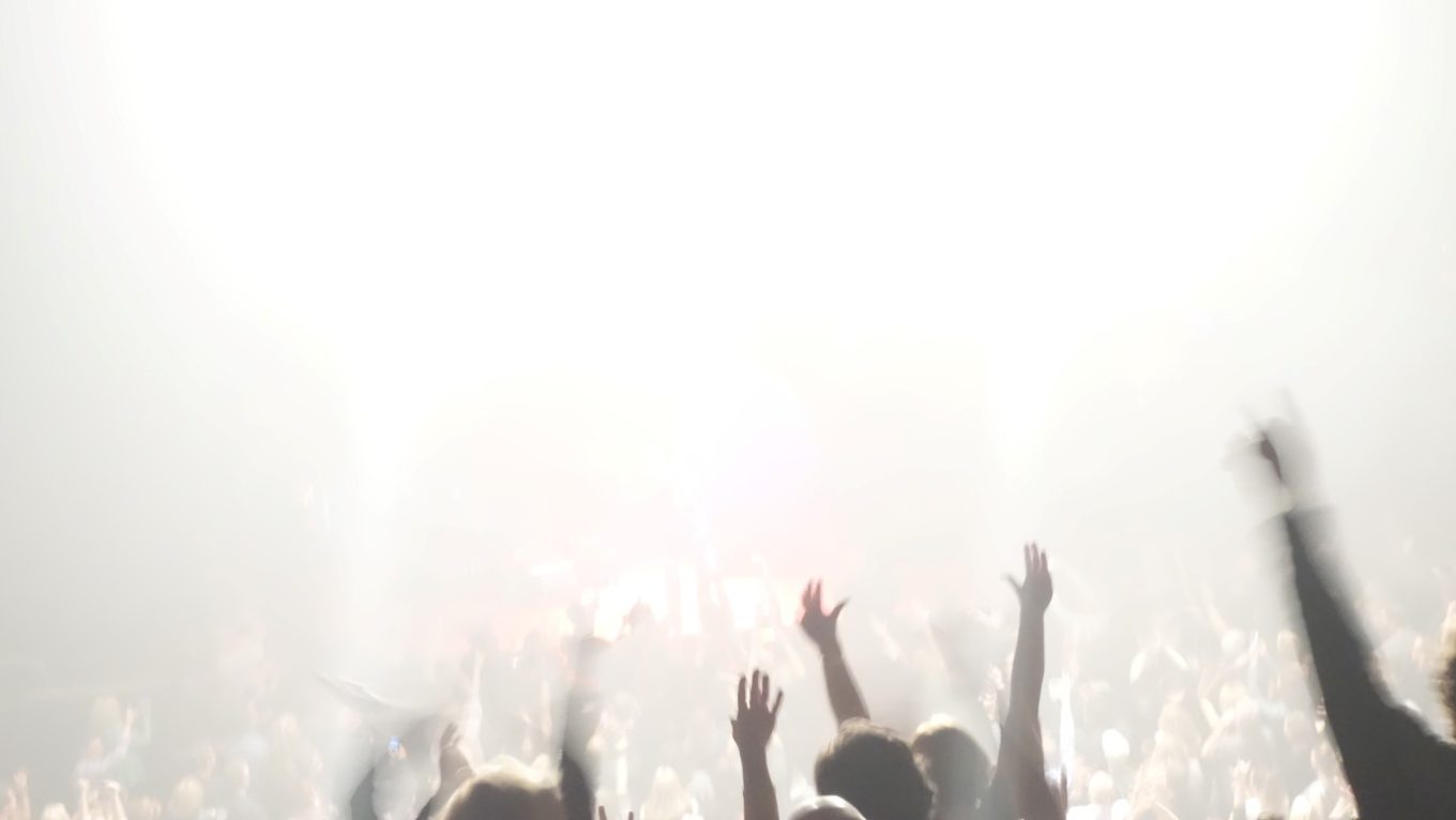 A crowd view with a bright light emitting from the stage!